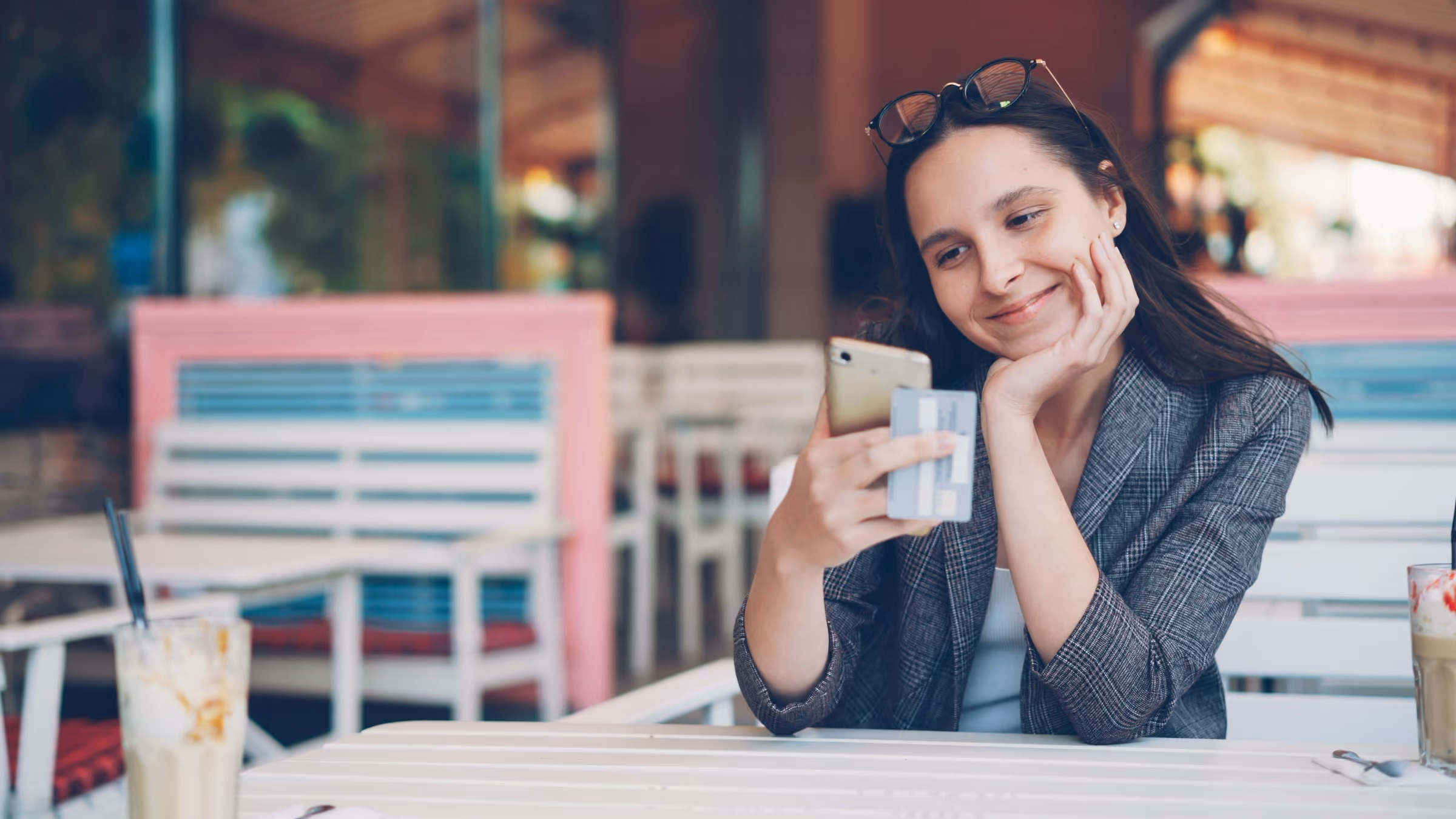 Junge Frau in einem Café, die zufrieden etwas auf ihrem Smartphone erledigt