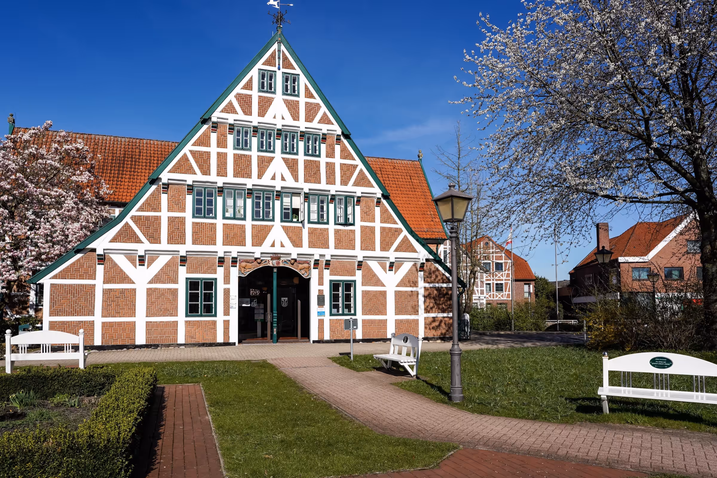 Fachwerkhaus in Jork im Frühling, daneben ein weiß blühender Baum unter blauem Himmel